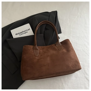 Close-up of a dark brown suede tote bag featuring a matte texture and leather handles