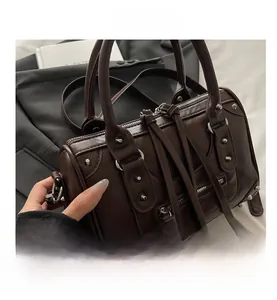 Close-up of brown leather pillow bag with silver studs and long fringe tassel zippers