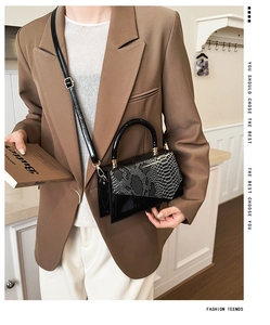 Detail of black crocodile texture handbag with snake pattern flap and metallic clasp