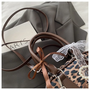 Dettaglio borsa leopardata con pizzo, perle e fiocco in nastro marrone elegante