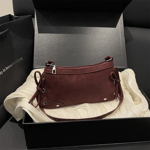 Burgundy suede handbag with bow details and silver rivets displayed in a black gift box