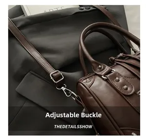 Detail of adjustable silver buckle on brown leather strap with metal studs and matte texture