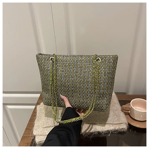 Detail of multi-color plaid tote bag with light green chain strap on a wooden table