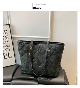 Close-up of black quilted tote bag featuring subtle camo pattern and leather handles