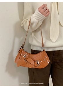 Detail of caramel crescent shoulder bag with metallic buckles and eyelet straps