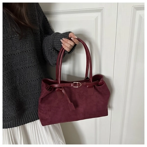 Detail of burgundy vintage tote bag with metal buckle on grey sweater and white skirt