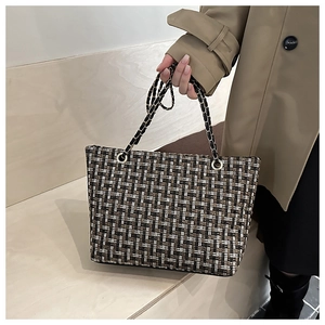 Close-up of classic plaid tweed tote bag with metal and leather chain strap detail