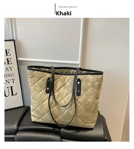 Detail of khaki quilted tote bag with black leather handles and gold rivet reinforcement