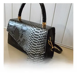 Detail showing the golden metal hardware hooks and snakeskin texture on the side of the bag