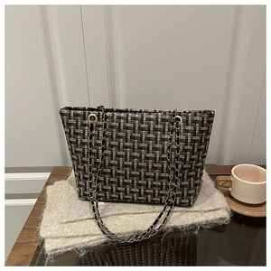 Detail of multi-color plaid tweed tote bag with gold chain strap on a soft knit blanket