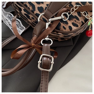 Dettaglio borsa leopardata con ciondolo a ciliegia e fiocco in nastro marrone