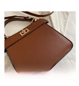 Détail d'un sac à main en cuir avec fermoir rotatif doré et finitions de couture précises