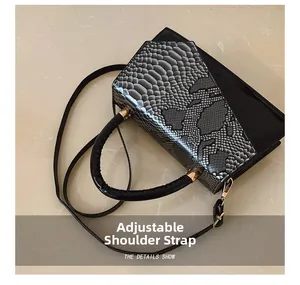 Detail of adjustable strap on silver snake pattern crossbody bag with gold hardware