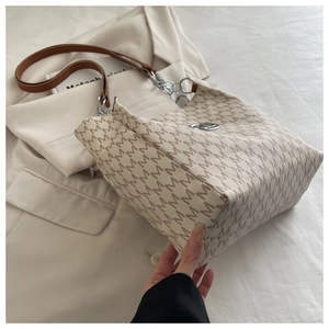 Détail d'un cabas beige avec motifs M marron et bandoulière en chaîne argentée