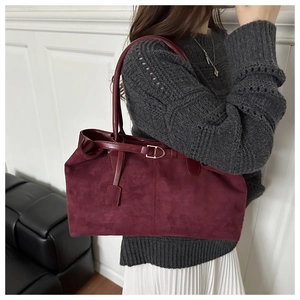 Detail of burgundy suede tote bag featuring leather straps and golden metal buckle