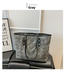 Detail of grey quilted tote bag with camo texture and gold metal accents on black seat