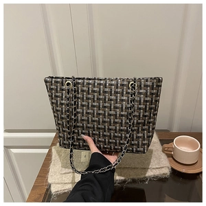 Close-up of the textured plaid tweed fabric and elegant gold chain strap on the tote bag