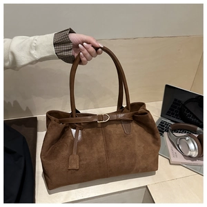 Detail of vintage brown suede tote bag with leather strap and metal buckle on office desk