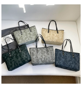 Detail of multi-color quilted tote bags with camo print and black leather handles