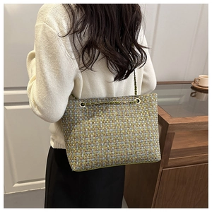 Detail of tweed texture and woven metal chain strap on an elegant shoulder bag