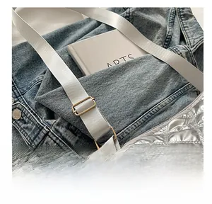 Detail of silver quilted shoulder bag featuring metallic finish and adjustable buckle strap