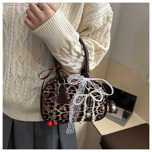 Dettaglio della borsa leopardata con fiocco in pizzo bianco e ciondolo ciliegia