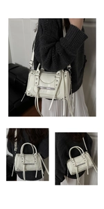 Detail showing silver studs and long fringe zippers on white leather boston bag