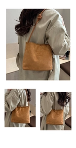 Detail view of khaki suede tote bag with knotted strap and classic engraved slogan