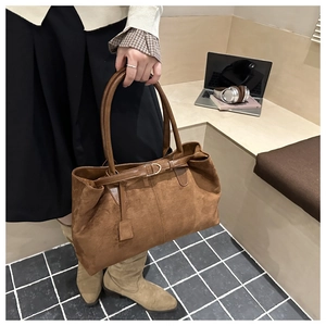 Detailed view of the brown faux suede tote bag featuring slim decorative buckle straps