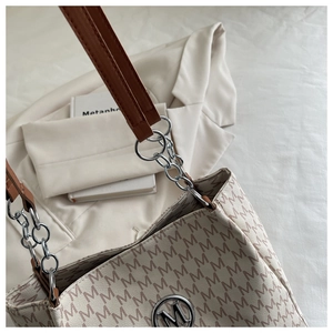 Vue détaillée du sac cabas beige avec motif M et bandoulières en cuir marron
