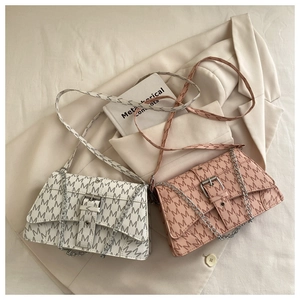 Close-up of elegant cream and pink leather crossbody bags with silver chain straps