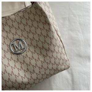 Détail du sac cabas beige avec motif M et boucle en métal argenté brillant