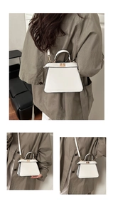 Detail of white leather Kelly bag showing gold twist lock and single top handle