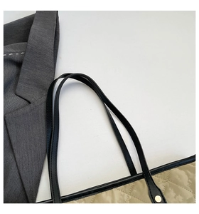 Detail of khaki quilted tote bag featuring black shoulder straps and gold metal rivets