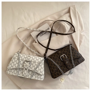 Detail view of monogrammed crossbody bags with chain straps and metallic buckles