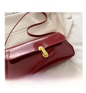 Close-up of a burgundy patent leather underarm bag with a gold metal clasp lock