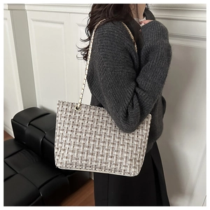 Detail view of the tweed weave and gold chain strap on this elegant tote bag for women