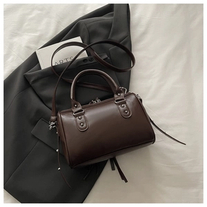 Detail view of a vintage dark brown Boston bag with silver rivets on a grey suit jacket