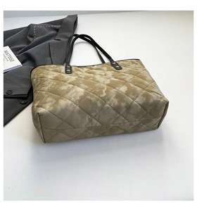 Flat lay of a large quilted tote bag with khaki tie-dye print and black leather handles
