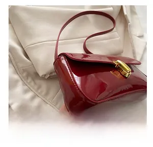 Close-up of wine red patent leather baguette bag featuring a gold metal buckle detail
