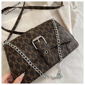 Detail of dark brown leather crossbody bag with M-pattern print and silver buckle hardware