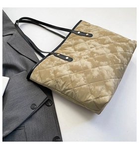 Detail of quilted tote bag featuring cloud pattern and sleek black shoulder straps