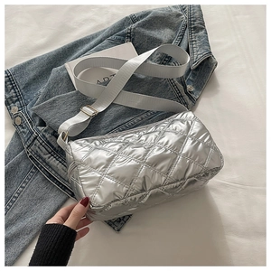 Close-up of silver quilted puffer bag texture with adjustable wide nylon shoulder strap