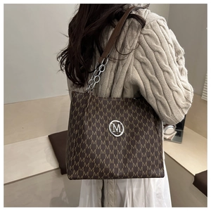 Gros plan d'un sac à bandoulière marron rétro avec motif monogramme et logo en métal
