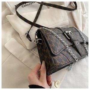 Detail of vintage monogram shoulder bag with chain strap on beige blazer background