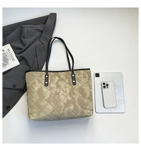 Quilted tote bag with cloud print and black straps shown in a lifestyle work setting