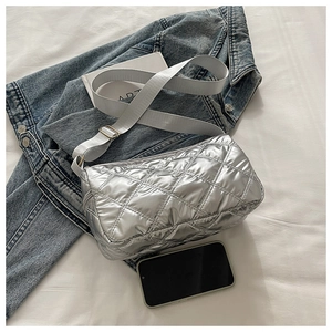 Close-up of silver quilted down crossbody bag featuring metallic finish and wide gray strap