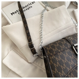 Detail of vintage brown shoulder bag with M-pattern print and metal chain strap