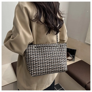 Detail of tweed checkered tote bag with chain strap styled on a khaki trench coat