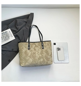 Detail of quilted tote bag with camo print, leather straps and metal rivets decoration
